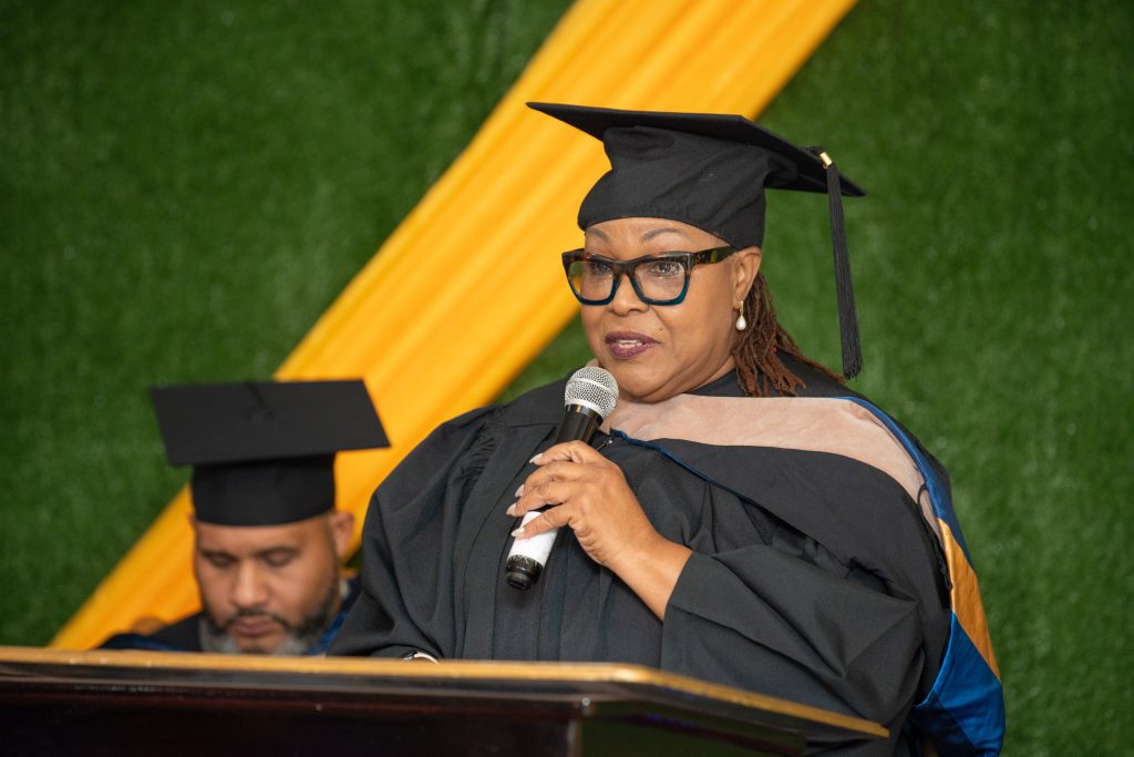 A speaker in academic regalia addressing the ceremony